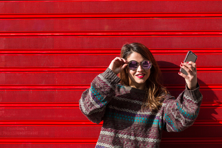 young female teen taking a selfie against a red backgroundの写真素材