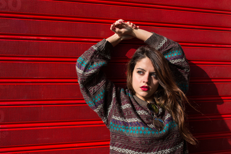 young woman posing outdoors on a sunny day against a red backgroundの写真素材