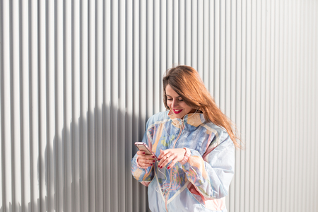 young woman teenager using mobile phone and earphones outdoorsの写真素材
