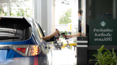 Bangkok Thailand 5 August 2020 - staff with protective mask serving starbuck coffee to customer at drive thru counter during coronavirus outbreak , Bangkok Thailandのeditorial素材
