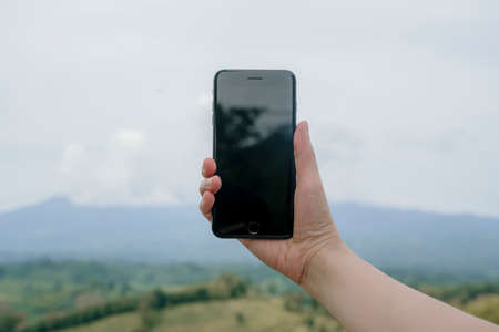 Woman hands holding smartphone isolated white screen on green nature bokeh backgroundの写真素材