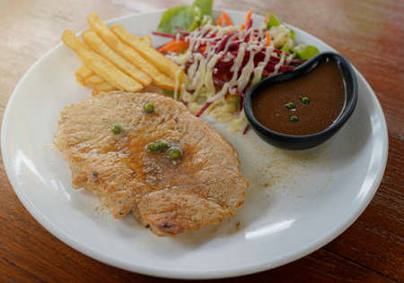 Tender grilled porterhouse steak served with crisp golden French fries and fresh green herb salad accompanied by a BBQ or tomato ketchup sauceの写真素材