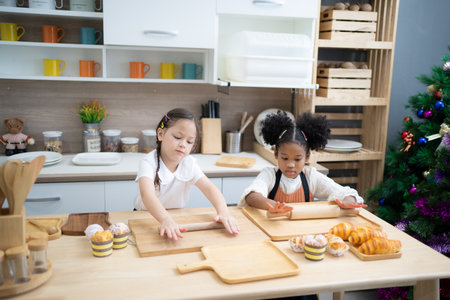 Two happy little kids siblings cooking together, rolling out dough, standing at wooden countertop in modern kitchen, cute homemadeの写真素材