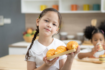 Happy little kids siblings cooking together, standing at wooden countertop in modern kitchen, preparing homemadeの写真素材