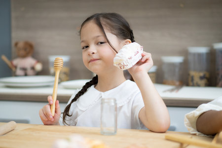 Happy little kids siblings cooking together, standing at wooden countertop in modern kitchen, preparing homemadeの写真素材