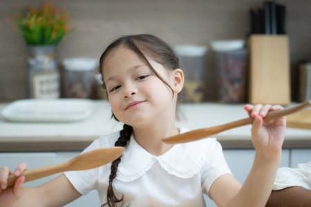 Happy little kids siblings cooking together, standing at wooden countertop in modern kitchen, preparing homemadeの写真素材