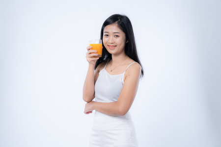 Beautiful asian woman drinking orange juice, healthcare, skin, beauty and wellbeing concepts, isolated on white backgroundの写真素材