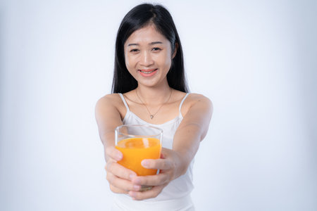 Portrait of beautiful young asian woman with orange juice on white backgroundの写真素材