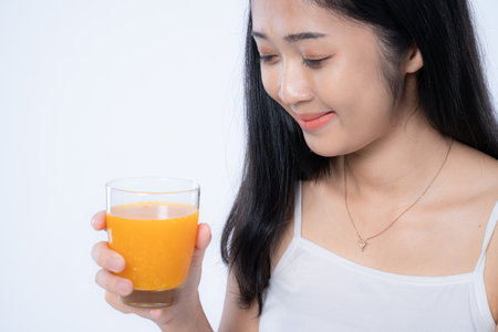 Beautiful asian woman drinking orange juice, healthcare, skin, beauty and wellbeing concepts, isolated on white backgroundの写真素材