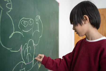 Happy school  Portrait of little boy writing on greenSchool, chalk and boy drawing on a board for child development, creativity and art for learning. Academic, creative and young kid student.の写真素材