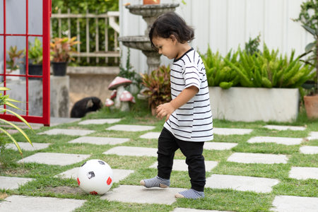 Cute little boy playing soccer with ball outdoors on soccer fieldの写真素材
