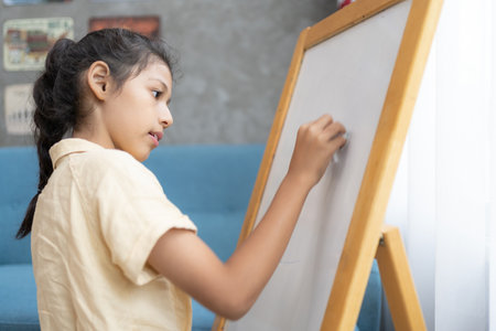 Little girl writing on empty whiteboard with a marker pen