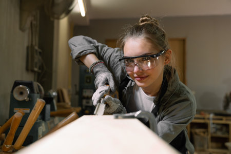 Female carpenter working with a circular saw in a carpentry workshopの写真素材