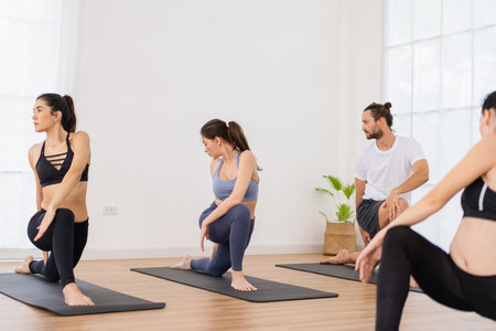 A yoga teacher and her group of students do basic yoga poses in a classroom in a fitness center in the studio.の写真素材