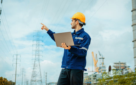 Portrait of a young engineer in a hardhat on the background of oil refineryの写真素材