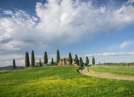 Typical Tuscan style farmhouse in the Val d'Orcia under a dramatic skyの写真素材