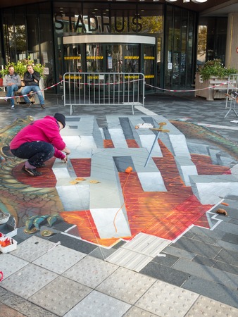 ALMERE, NETHERLANDS - 23 OCT. 2017: Unknown artist works on a street painting that shows the power of 3D optical illusion. Once a year the city of Almere allows artists to create street artのeditorial素材