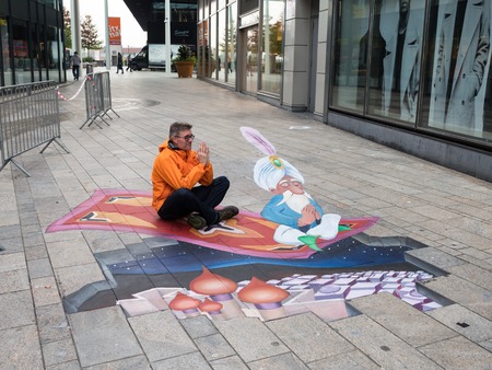 ALMERE, NETHERLANDS - 24 OCT. 2017: Unknown man shows the power of 3D optical illusion of a street painting of 'The Arabian Nights' by an unknown artist in Almere.のeditorial素材
