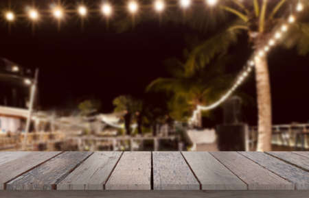 Wooden table top on blur resort  background in night dinner or fullmoon party.Place food and juice by restaurant.For montage product display or design key visual layout.View of copy space.の写真素材