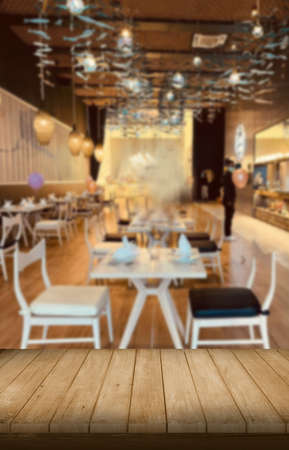 Wooden table top on blur restaurant or cafe background with warm light.Place food,coffee,tea or...