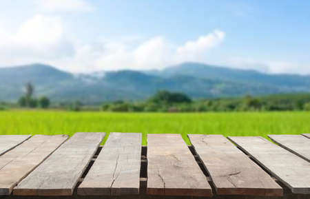 Wooden table top on blur rice field and mountain background.For place food,drink or health care business.fresh landscape and relax season concept.View of copy space.の写真素材