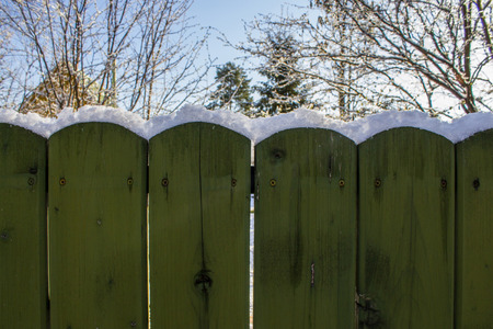 Snow on the fence at sunny dayの写真素材