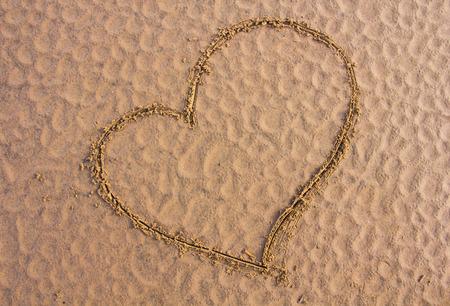 Heart sign drawn on the sandの写真素材