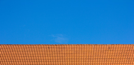 Red rooftop of tiles against blue skyの写真素材
