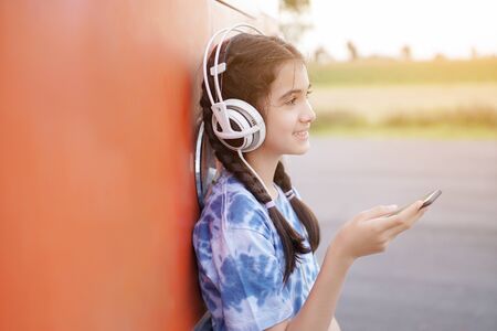 Asian girl thai  sitting in headphone see Mobile Phone on the grass listen the musicの写真素材