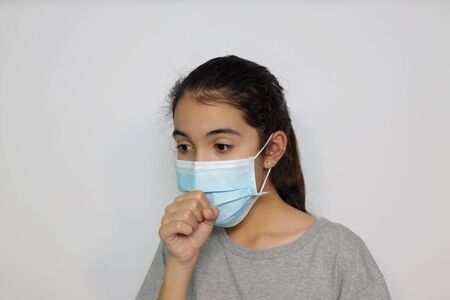 An Asian girl in an infectious disease prevention mask shows sick gestures and influenza health care concepts with a white screen background.の写真素材