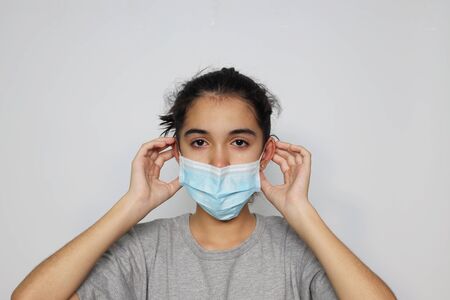 Asian girl in an infectious disease mask shows sick and sad gestures with tears, a health care concept to prevent the flu with a white screen background.の写真素材