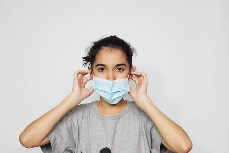 Asian girl in an infectious disease mask shows sick and sad gestures with tears, a health care concept to prevent the flu with a white screen background.の写真素材