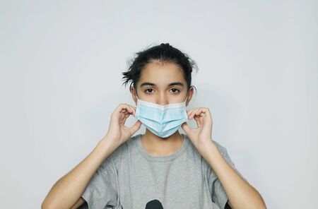 Asian girl in an infectious disease mask shows sick and sad gestures with tears, a health care concept to prevent the flu with a white screen background.の写真素材