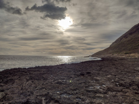 An ominous looking shoreline underneath a cloudy evening sky. Taken at Yokohama Bay on Oahu, Hawaii.の写真素材