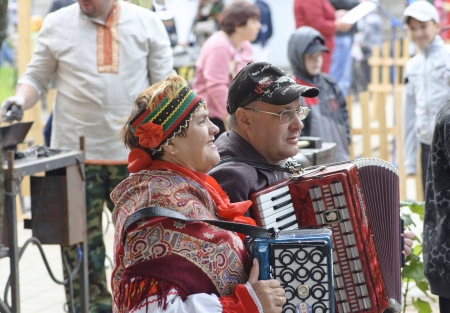 elderly woman in russian national suit and elderly man play on accordion on holiday Antonovskie apple in old russian city Eliceのeditorial素材