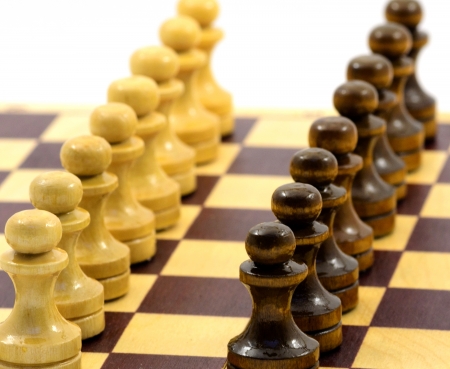 formation from black pawn against building from white pawn on chess board on white background