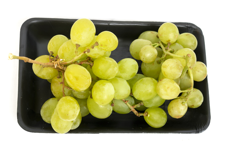 Top view of green grape bunch in black tray with white isolated backgroundの写真素材