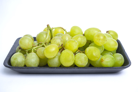 A bunch of green grape in black tray with white isolated backgroundの写真素材