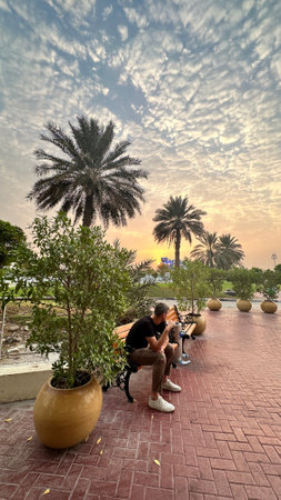 A man cherishes the calm sunrise moment, seated on a park bench in Dubaiのeditorial素材