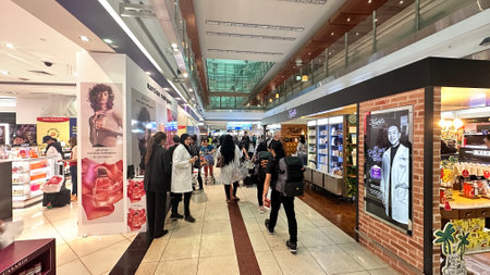 DUBAI, UAE. 16 SEPTEMBER 2023. Travelers traversing through duty-free towards departure gates, embodying airport commerceのeditorial素材