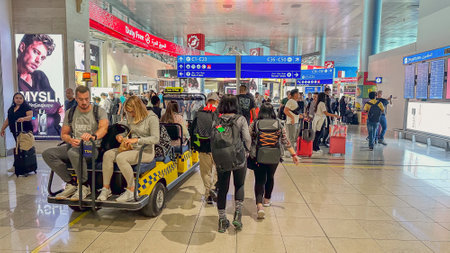 DUBAI, UAE. 16 SEPTEMBER 2023. travelers briskly walking toward the departure gate, with a visible buggy transporting people nearbyのeditorial素材