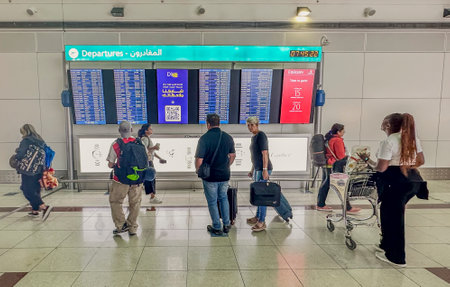 DUBAI,UAE. 16 SEPTEMBER 2023. Traveler stands in the bustling airport, studying the departure information board with focused anticipation for the imminent journey aheadのeditorial素材