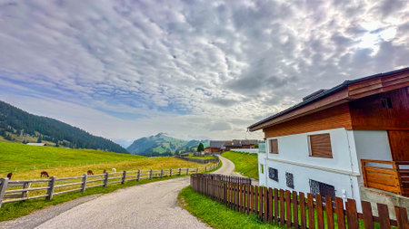 Nestled in Alpe di Suisi, a cozy house stands against soaring peaks, rendering a picturesque scene of mountainous tranquillityの写真素材