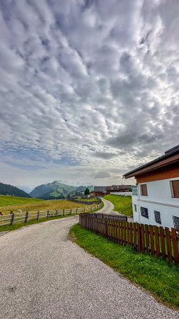 In the Alpe di Suisi's heart, a quaint house sits amidst towering peaks, encapsulating a serene mountain living imageの写真素材