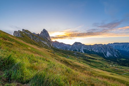 Golden sunrise at Seceda, Dolomites, Italy, A breathtaking spectacle unfolds, casting warm hues on the rugged landscape and meadows, creating a serene and radiant morning panorama.の写真素材