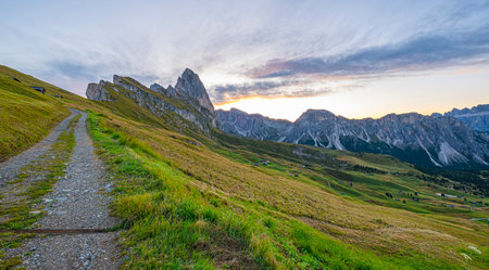 Dolomites' Seceda at sunrise, A golden spectacle graces the rugged landscape, casting warmth on iconic peaks, an enchanting start to the day in Italy's stunning mountains.の写真素材