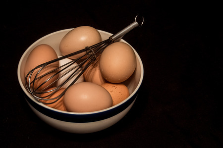Farm fresh eggs in a bowl with a whisk