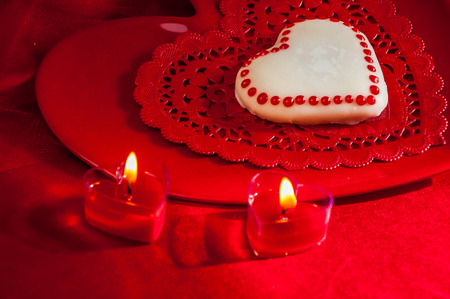 Red heart shaped votives burning with heart shaped cookie and plateの写真素材