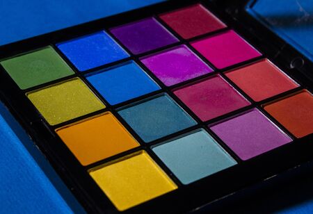 Palette of colored eyeshadows, close-up on blue background.の写真素材