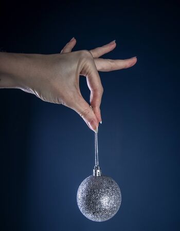 woman hand with Christmas ball, on a blue background.の写真素材